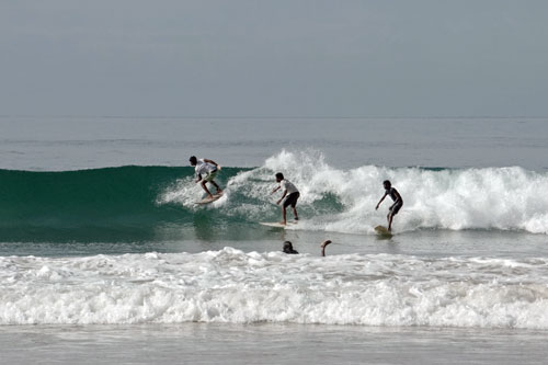 three surfers on a wave, CA